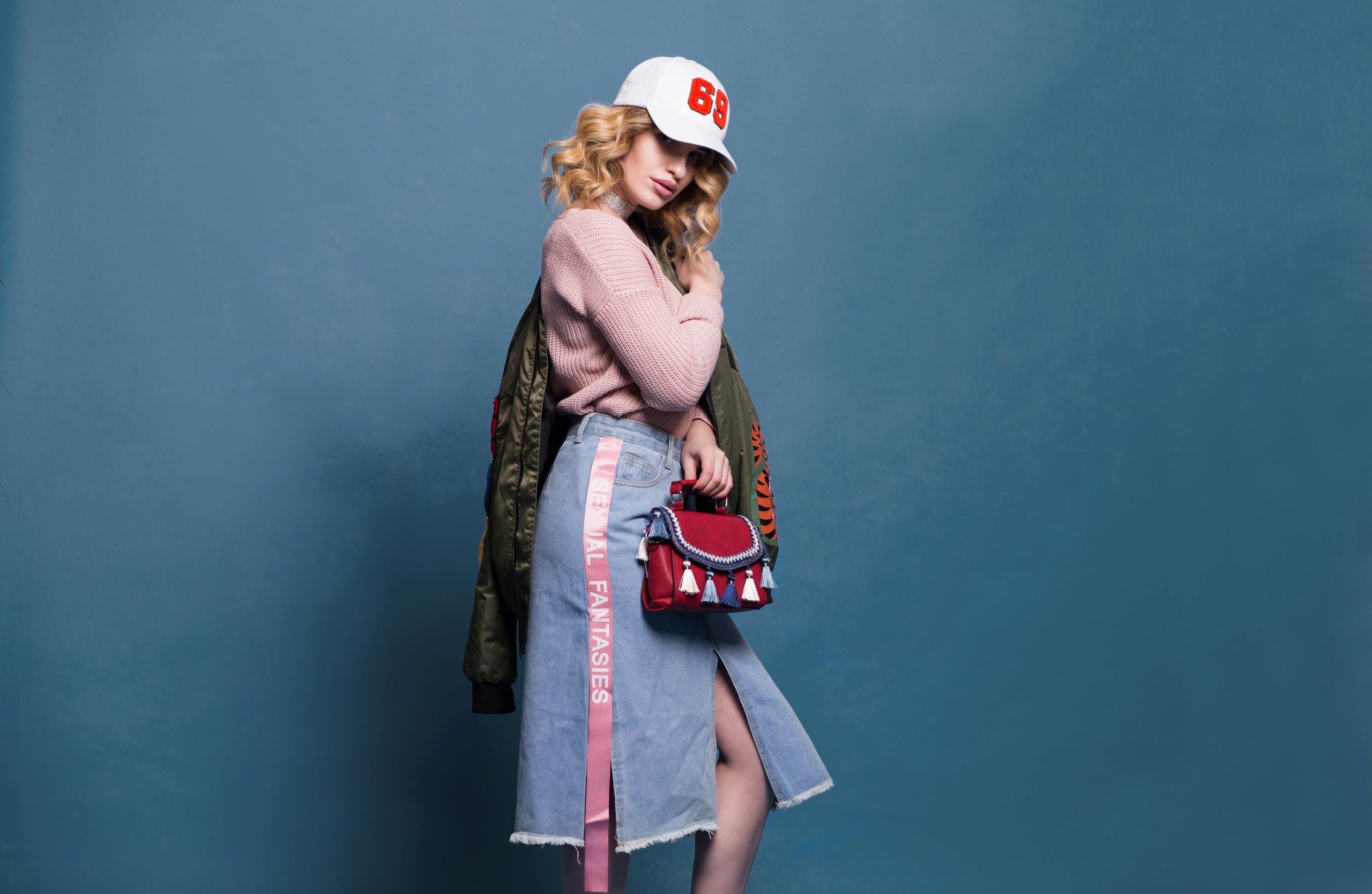 Trendy fashion model poses in a stylish studio setting, showcasing a chic outfit with accessories.